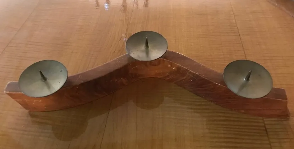 Candelabra purani ke saath do candle holder ke saath curved base par ek wooden table.