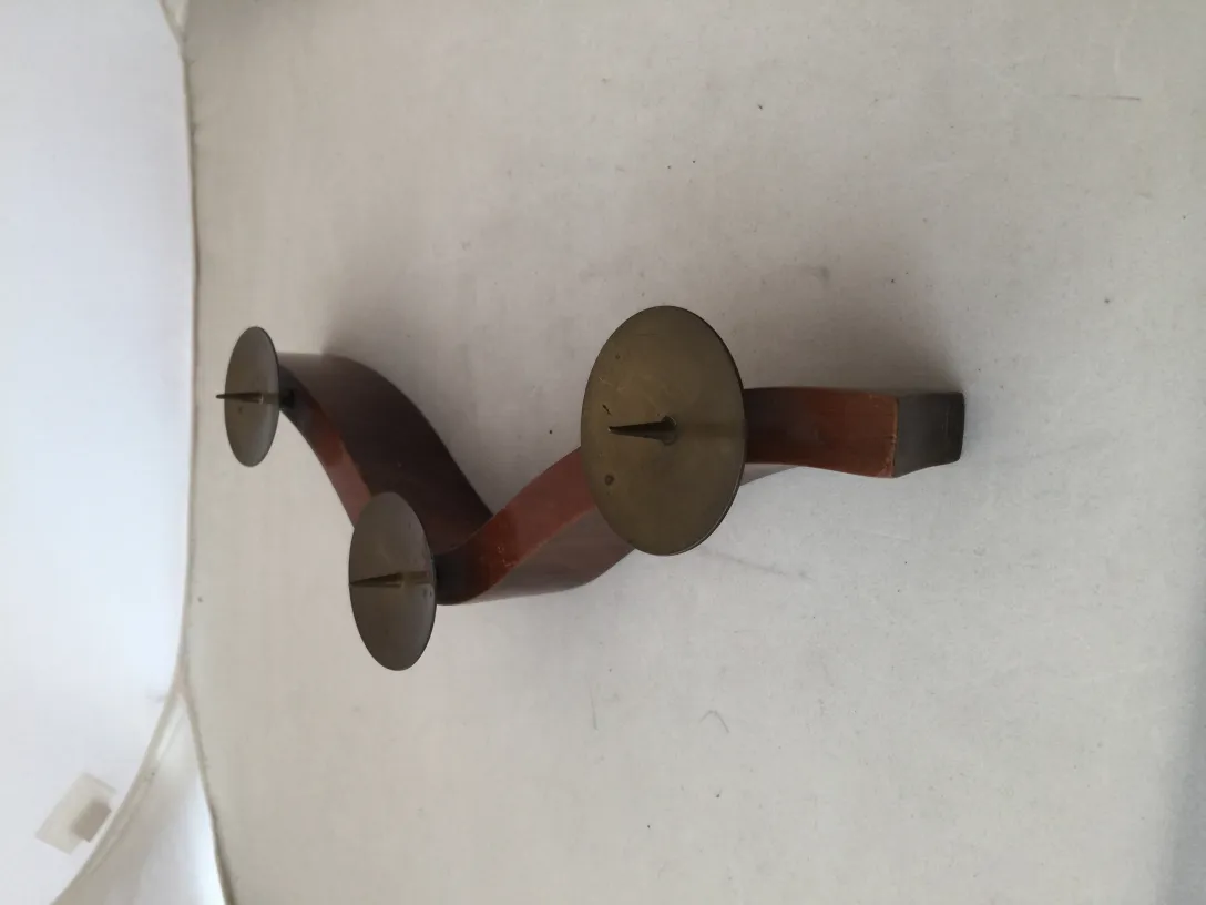 Candelabro antico a tre bracci con base curva, esposto in un ambiente neutro.