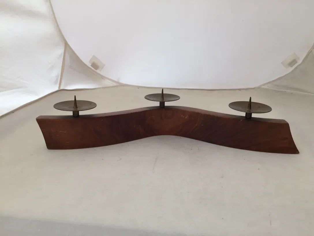 Candelabro antico con forma curva e due portacandele su sfondo bianco.