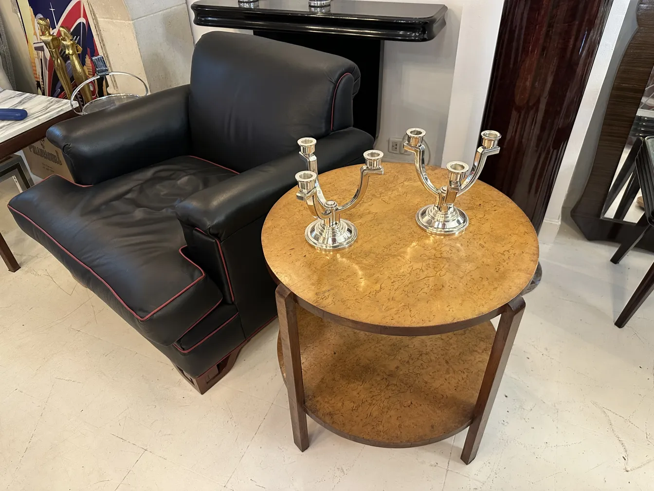 Candelabre ancien à trois bras sur une table ovale. Arrière-plan avec un fauteuil noir.