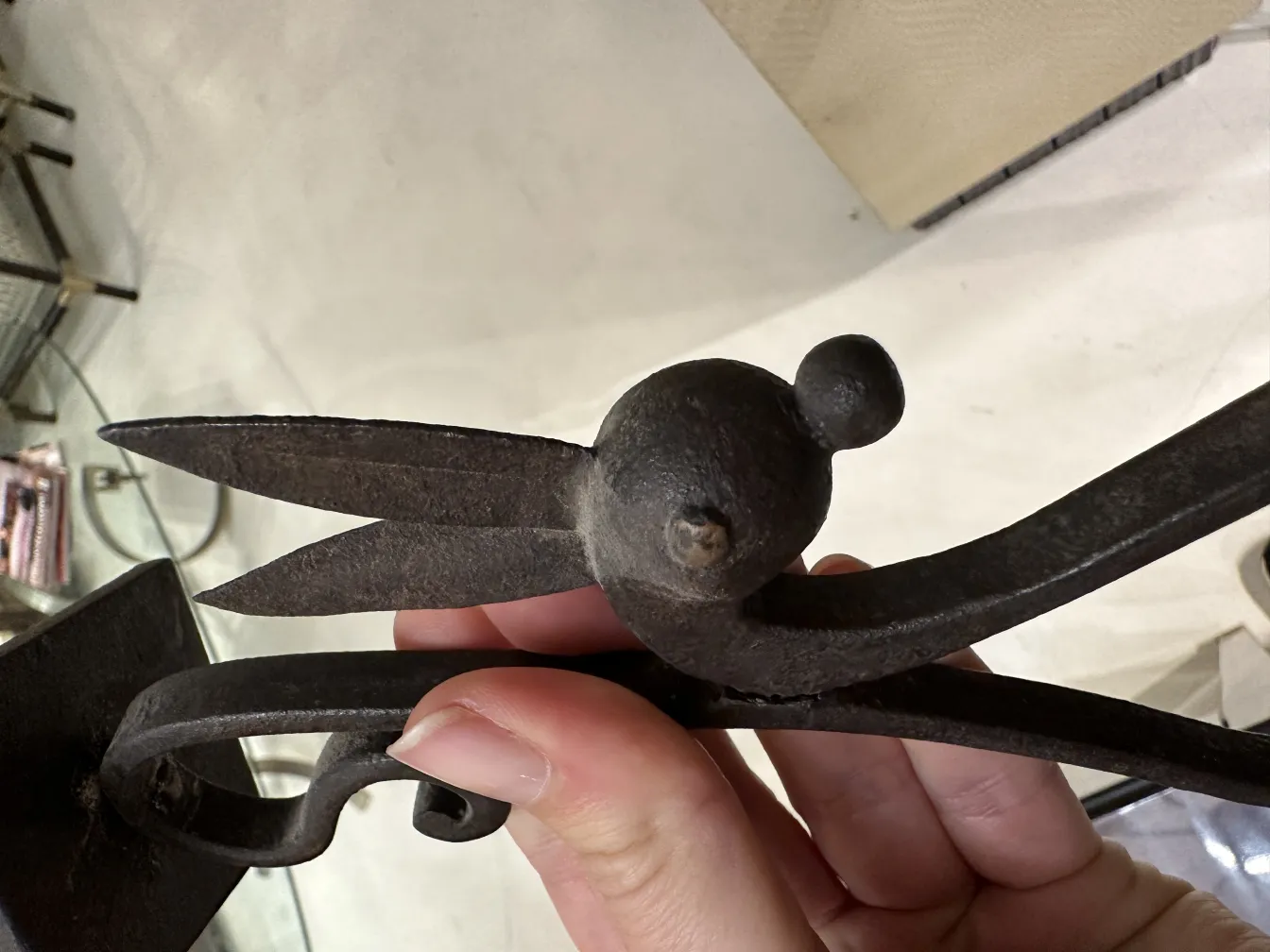 Primo piano di un candelabro antico decorativo, con dettagli a forma di foglia e una finitura rustica in un ambiente elegante.