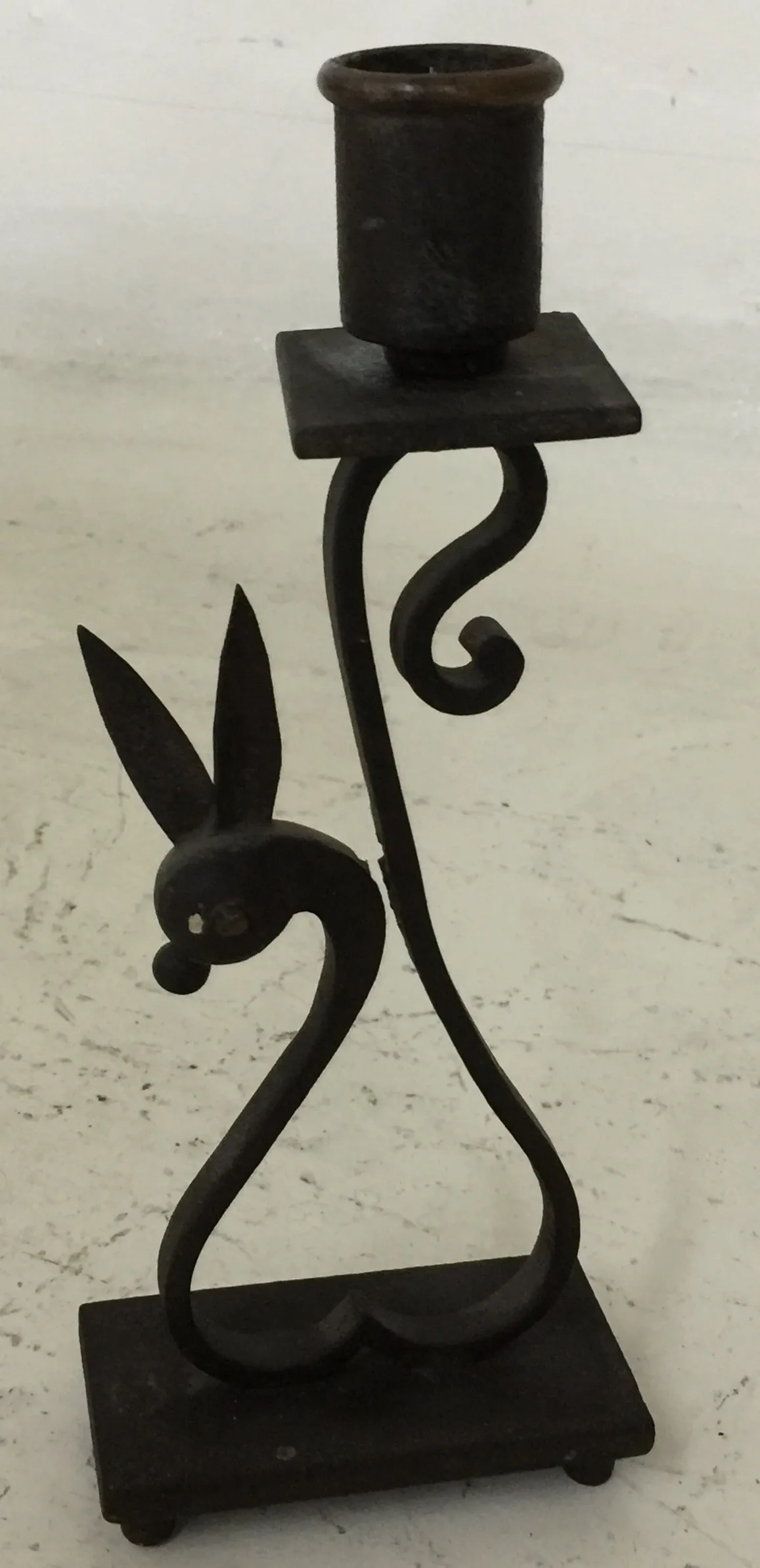 candelabro antigo com base quadrada e figura de coelho, cor escura