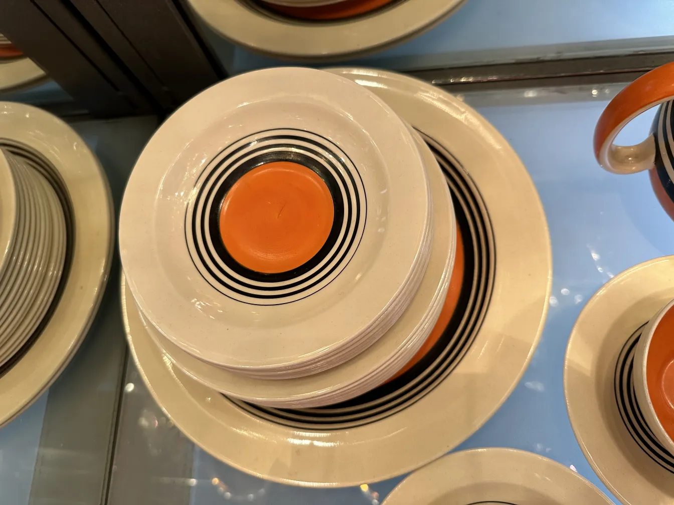 Conjunto de chá antigo com pratos e xícaras de design colorido e geométrico, ambiente elegante.