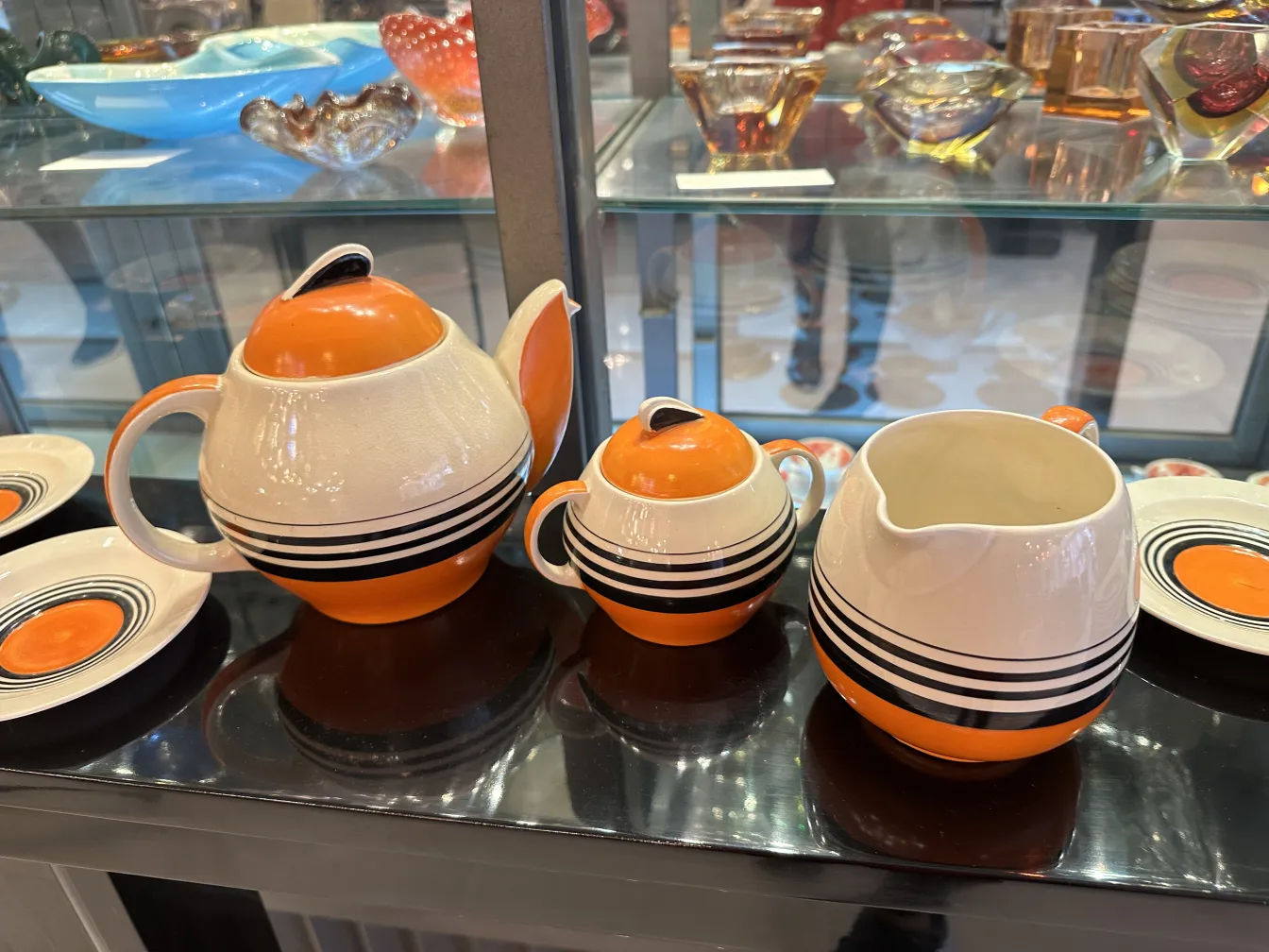 Service à thé ancien avec design stylisé en céramique, comprend une théière et des tasses aux couleurs orange et blanche.