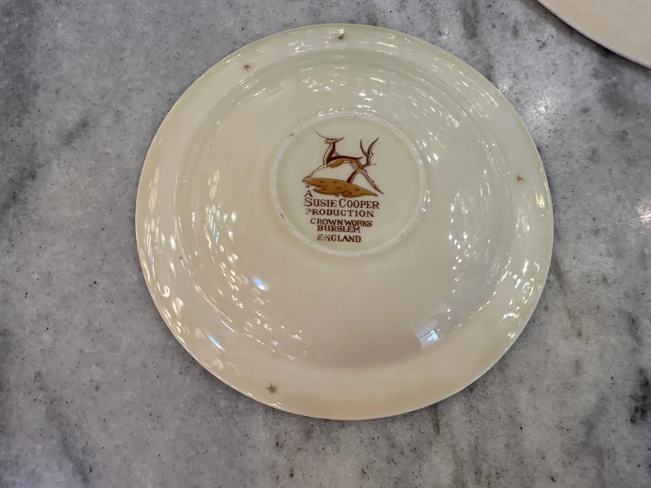 juego de té antiguo con un plato decorativo, color claro y diseño sencillo, sobre una mesa de mármol