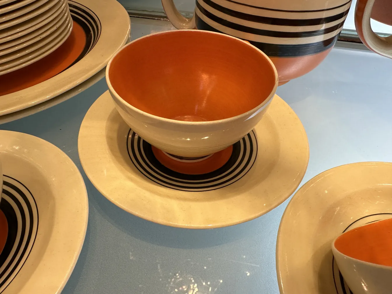 Antique tea set with geometric designs in warm tones, includes plates and cups.