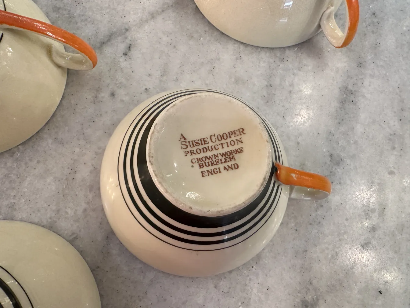 juego de té antiguo con taza de color naranja, patrones en blanco y negro sobre fondo claro