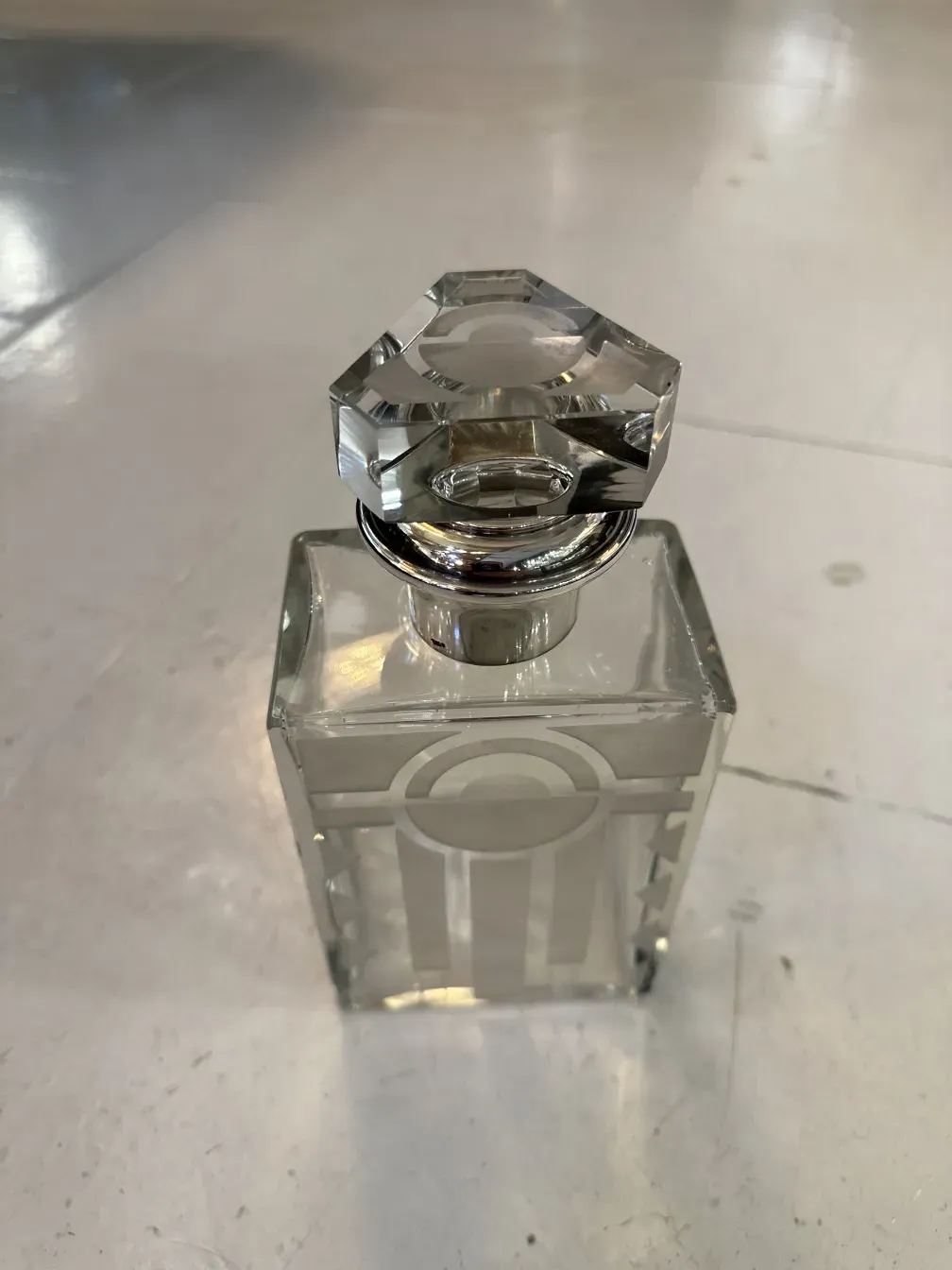 古老的方形瓶子，带有装饰性盖子，底部透明。