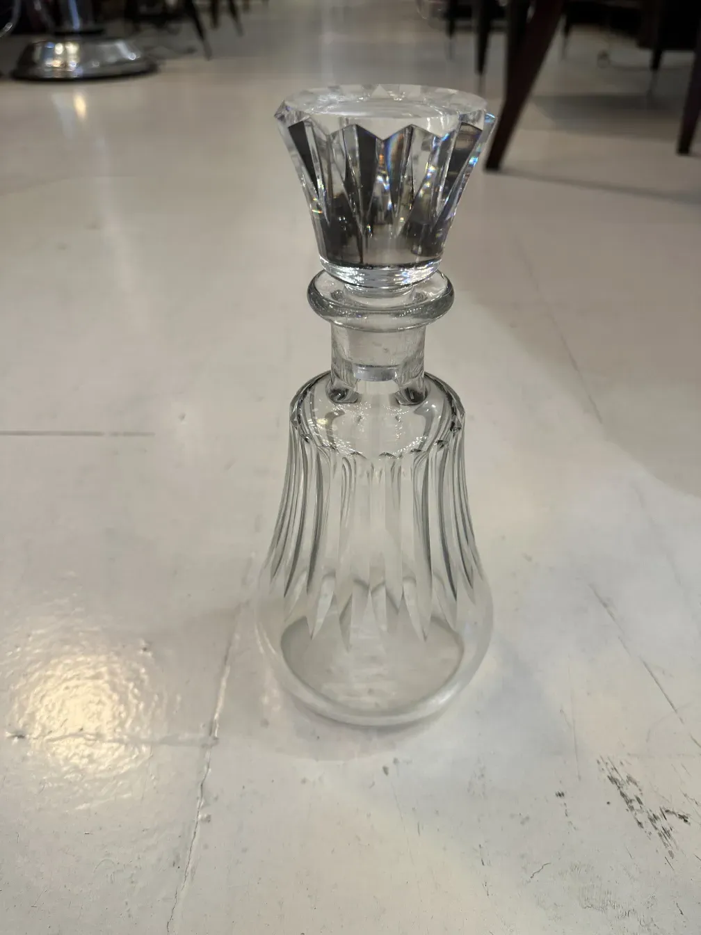 Garrafa antiga de vidro com detalhes na tampa e na base, fundo neutro