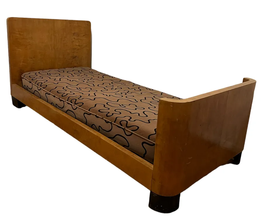 Lit ancien avec un matelas imprimé présentant des motifs ondulés.