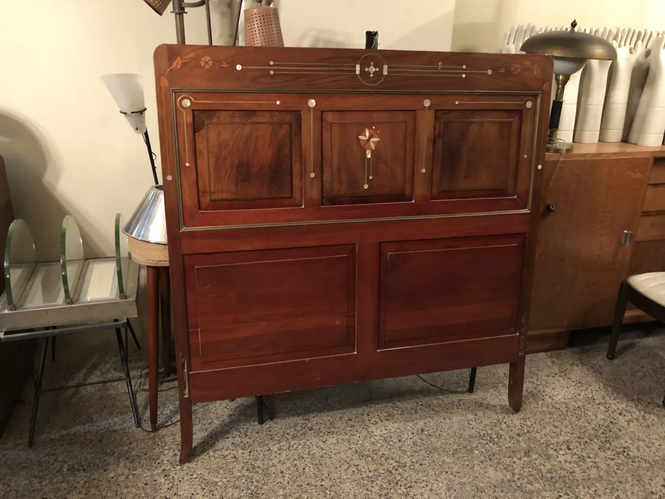 装飾的なヘッドボードがある古いベッドがヴィンテージのセットに置かれています。