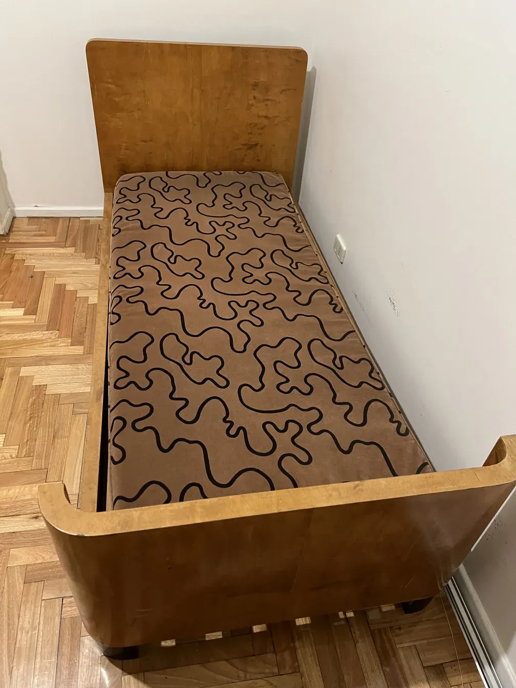 Cama antiga com design geométrico e almofada em um ambiente acolhedor