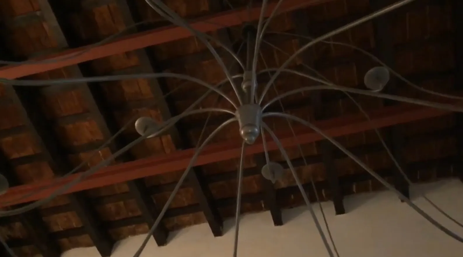 Tre lampade a sospensione antiche con bracci curvi in un ambiente rustico