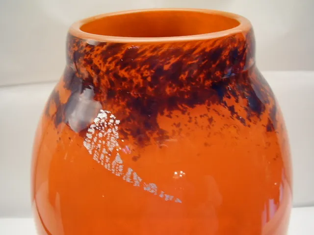 Verre tubulaire signé orange avec des motifs sombres.