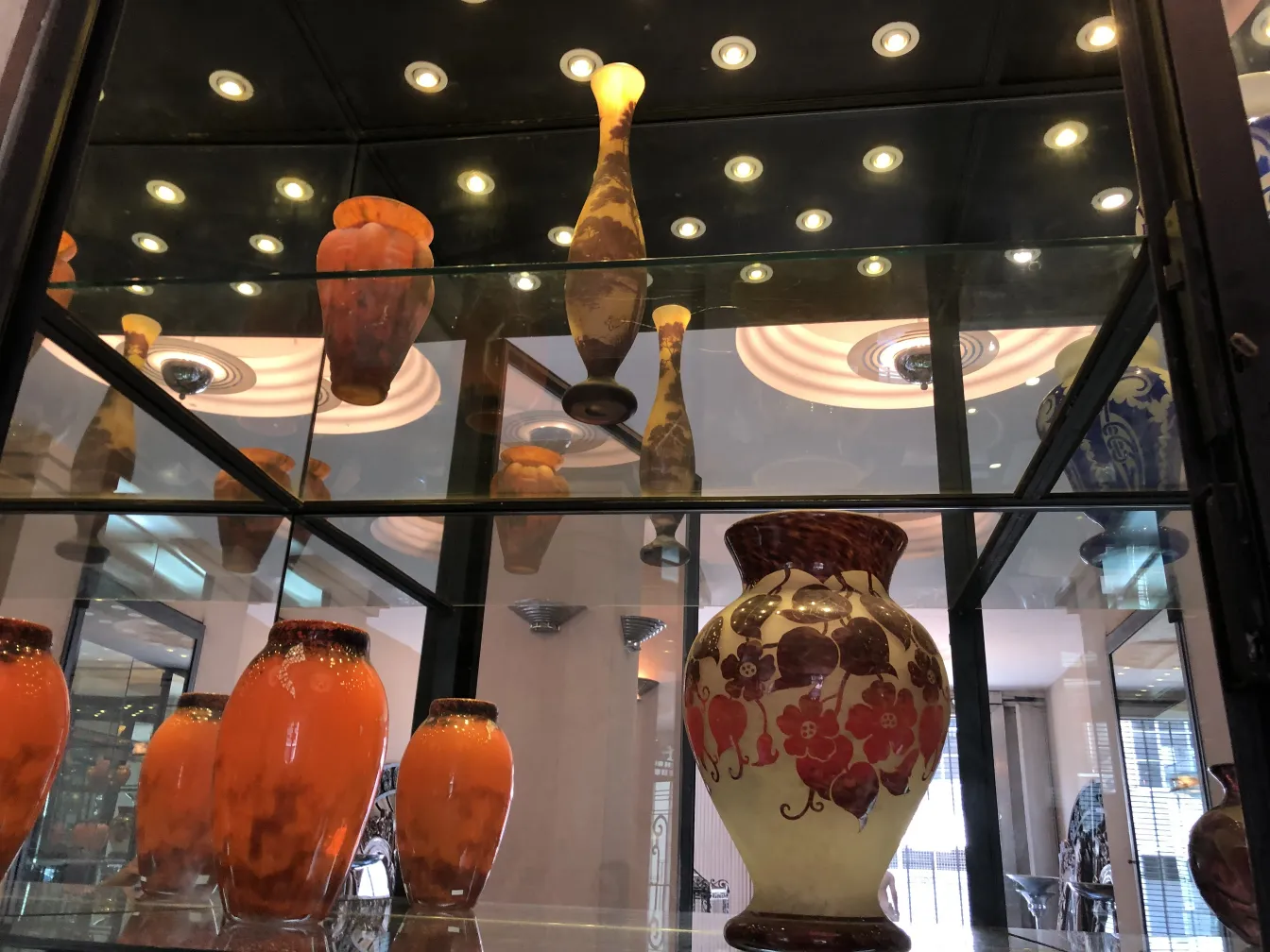 Vasos de vidro antigo em vitrine, destacando um vidro assinado Muller Fres