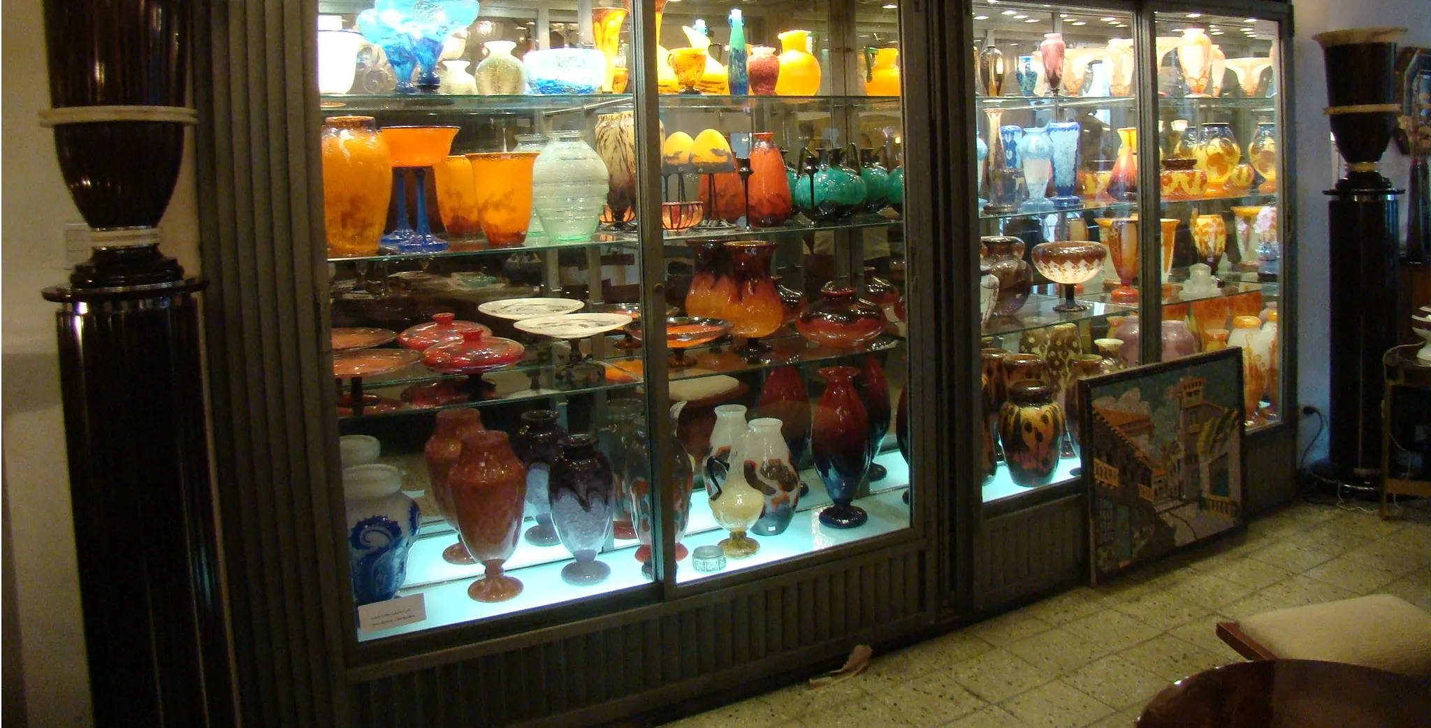 Vitrine mit verschiedenen Vasen und antikem Glas, darunter das signierte Glas von Muller Fres.