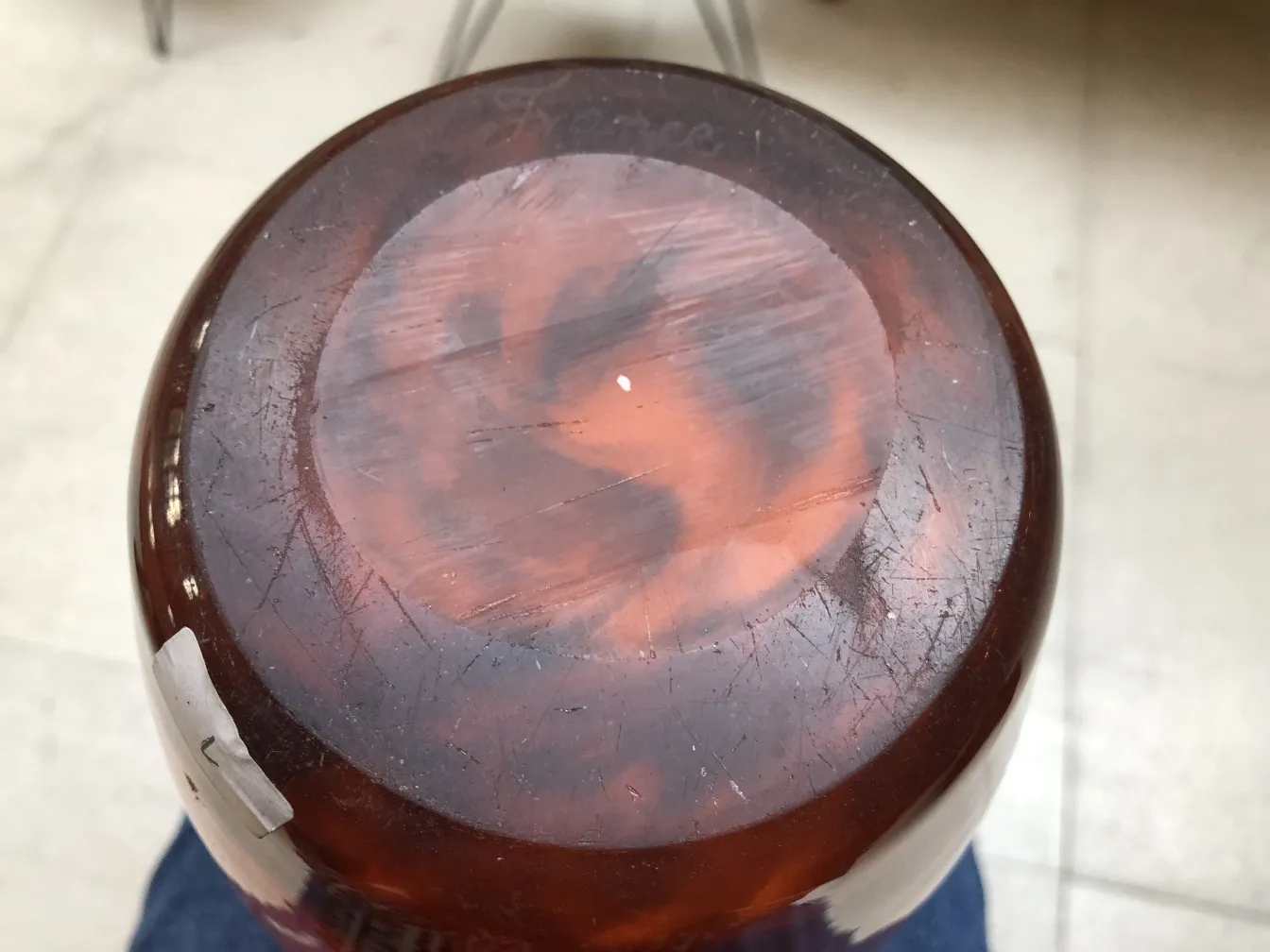 Vidrio firmado Muller Freres, un antiguo objeto decorativo con detalles únicos, colocado sobre una superficie neutra.