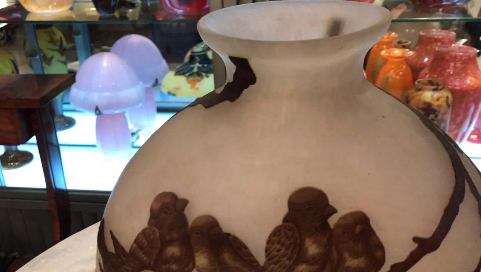 Vue d'un verre signé antique Muller Fres avec des oiseaux décoratifs, fond incluant d'autres objets anciens.