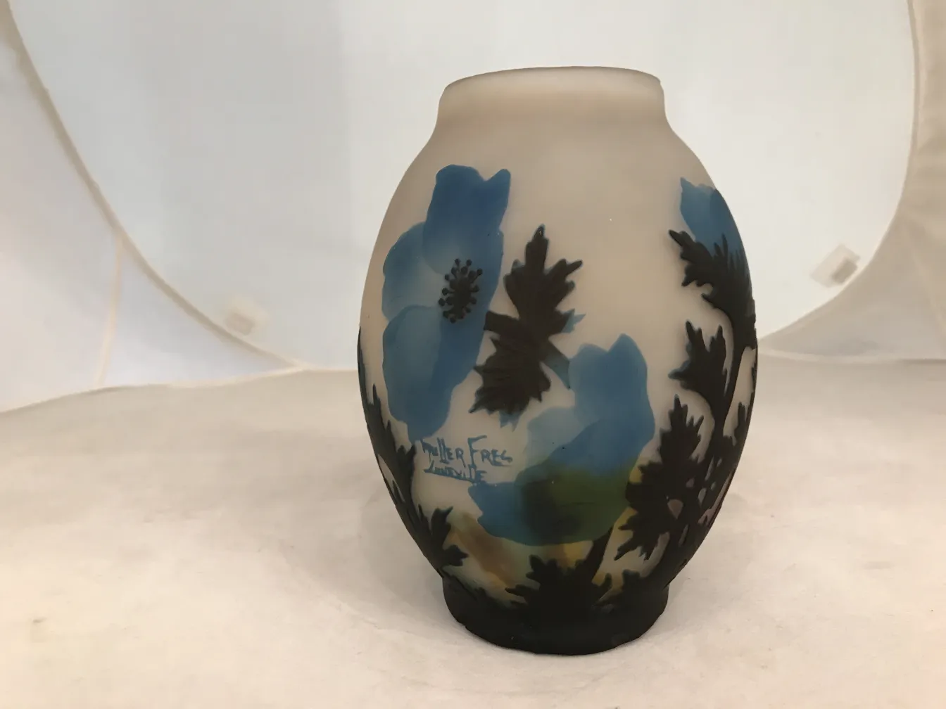 Signiertes Glas Muller Fres mit blauen floralem Muster auf hellem Hintergrund.