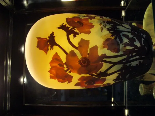 Vaso de vidro assinado com desenhos florais coloridos.