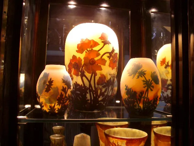 Vidro assinado de Muller Freres com design floral, apresentado em vitrine antiga.