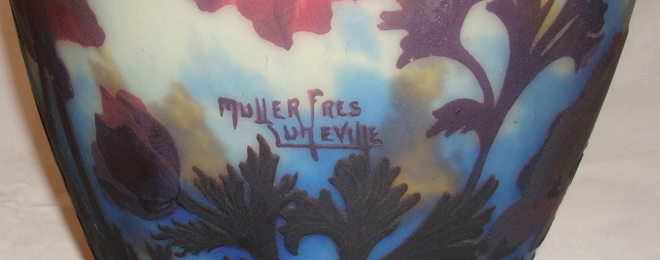 Vidrio antiguo firmado por Muller Freres con diseño floral en tonos azules y morados.