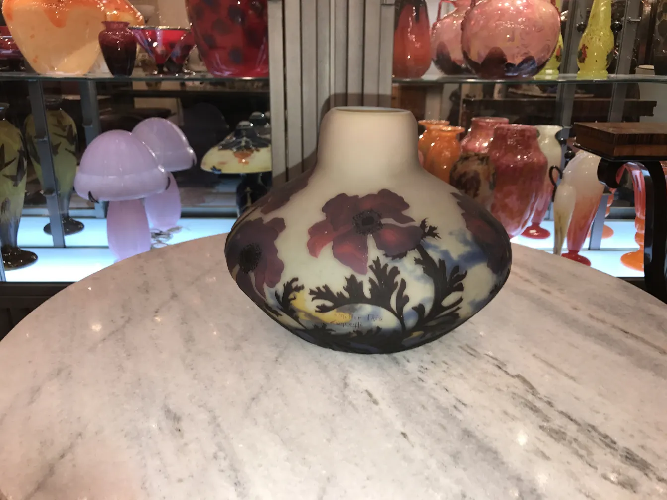 Vase ancien signé Muller Fres avec des fleurs rouges et vertes.