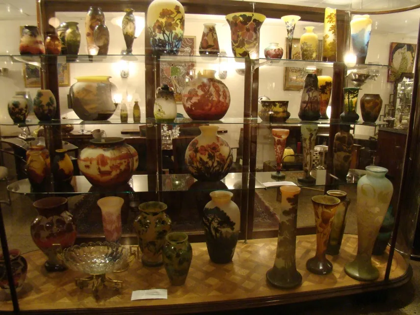 Collection of antiques featuring signed glass Muller Fres displayed in showcase.