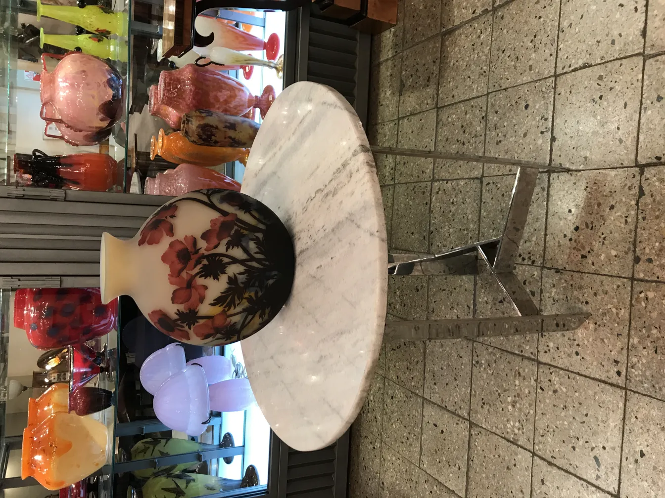 Vaso de vidro assinado Muller Fres com decoração floral sobre uma mesa