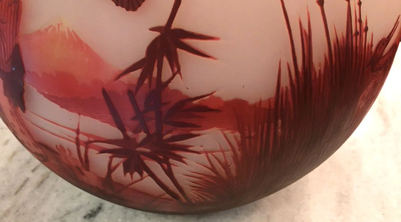 Verre ancien signé par Muller Fres, avec des détails rouges et un paysage naturel.