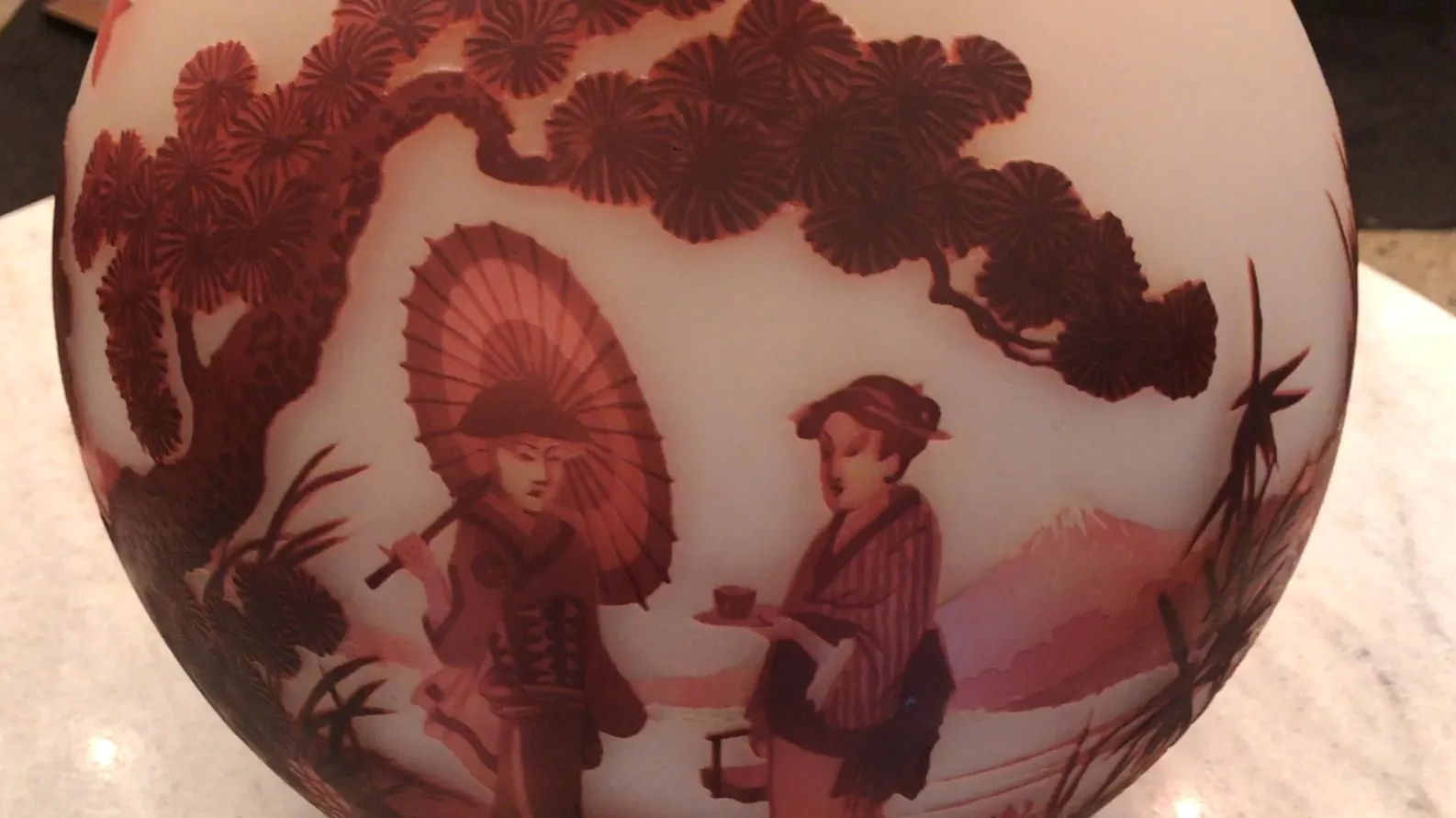 Vidrio antiguo con figuras en relieve de personas y paisaje.