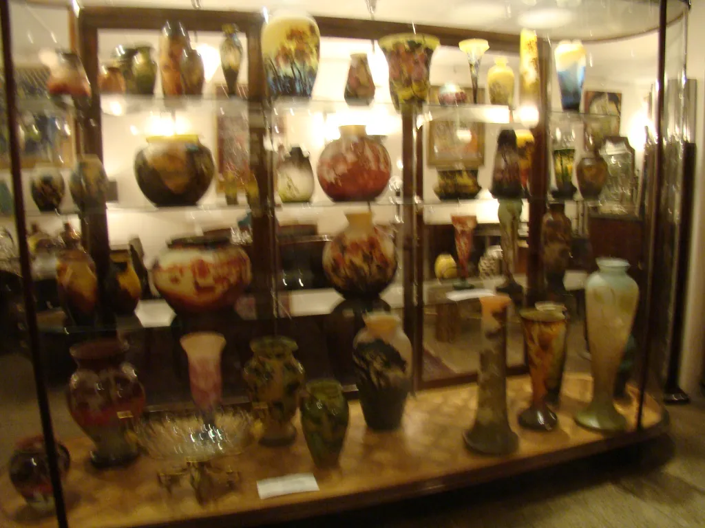 showcase with various colored antiques, including signed glass muller fres