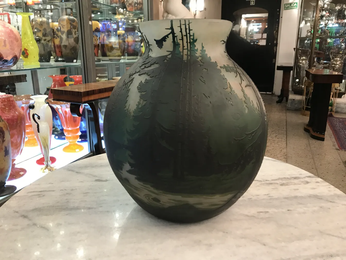 antique vase with forest details and signed glass Muller Fres, surrounded by other decorative items