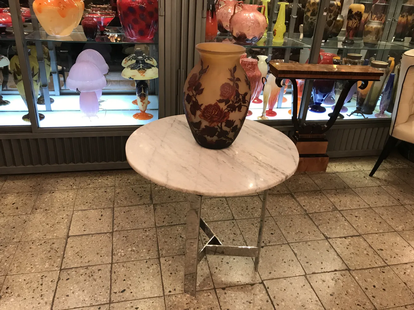 古典花瓶放在大理石桌子上，背景是签名玻璃Muller Fres。