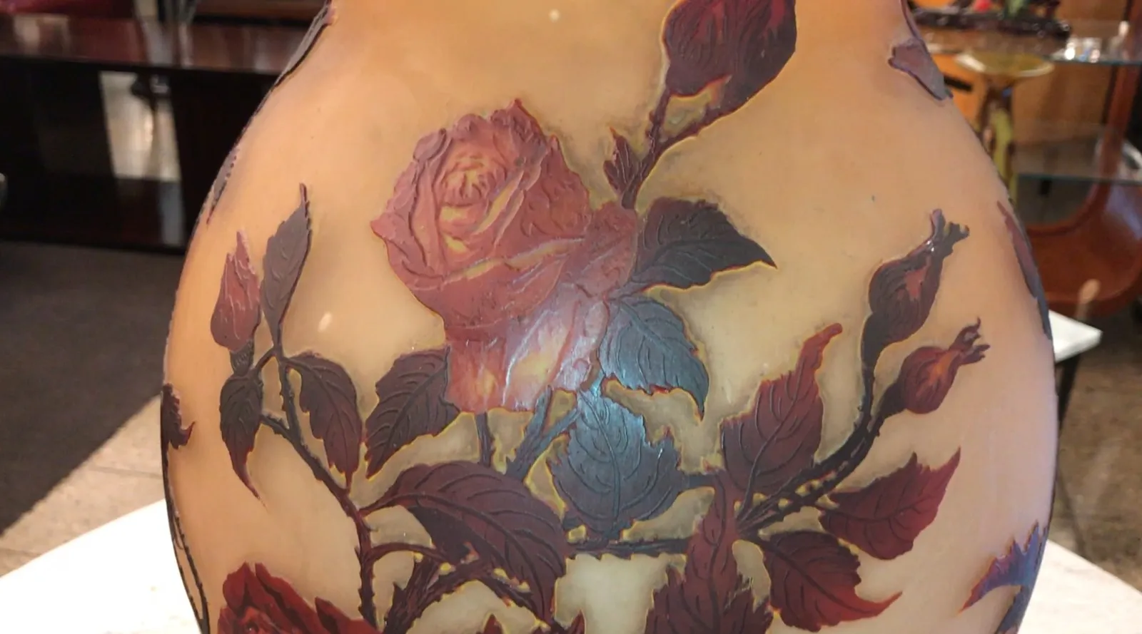 Antigüedad con flores en relieve y fondo claro, firmado.