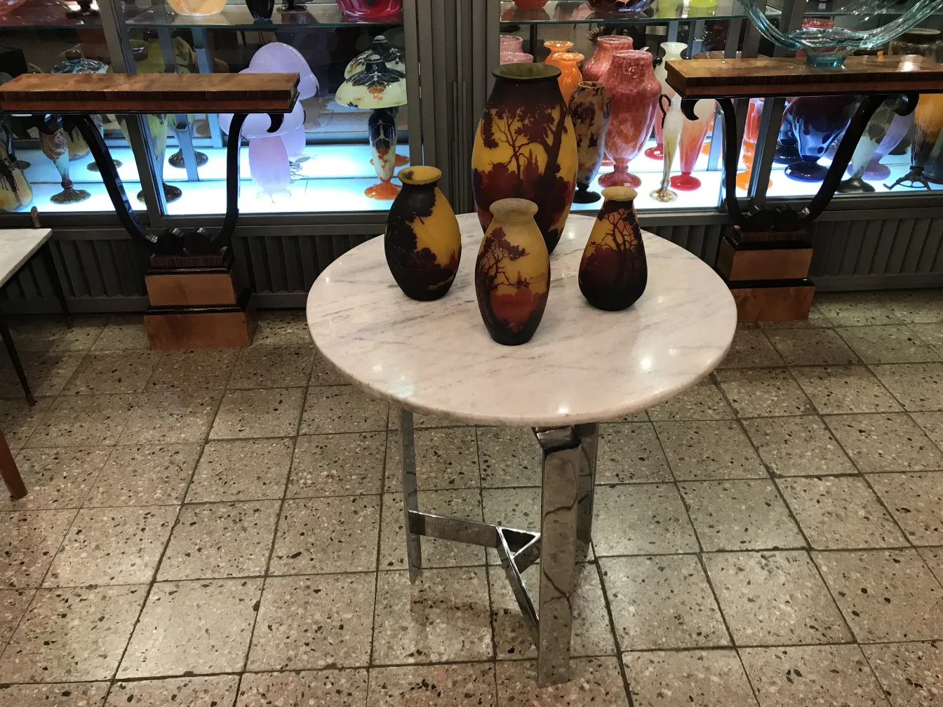 Cuatro floreros decorativos en tonos cálidos sobre una mesa de mármol.