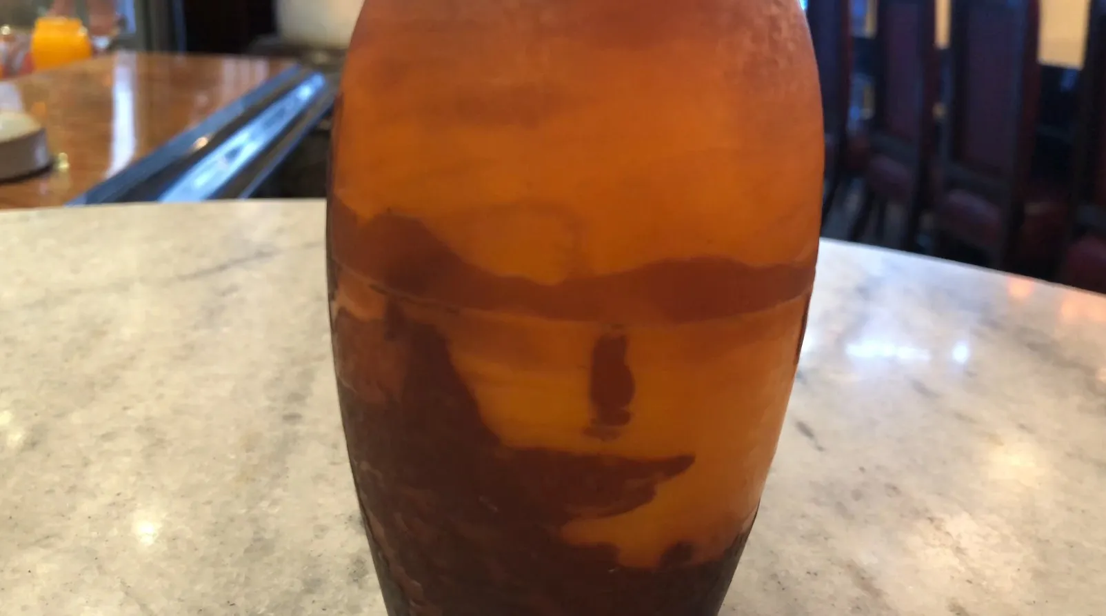 Vidro antigo assinado por Muller Fres com decoração única em um ambiente elegante de restaurante.