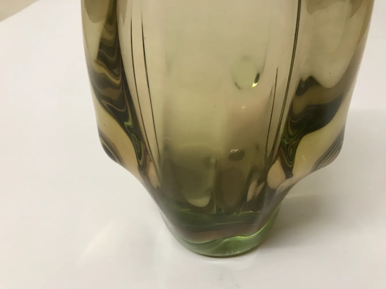 Vaso de murano antigo em tons verdes com design curvilíneo, embelezando um ambiente clássico.