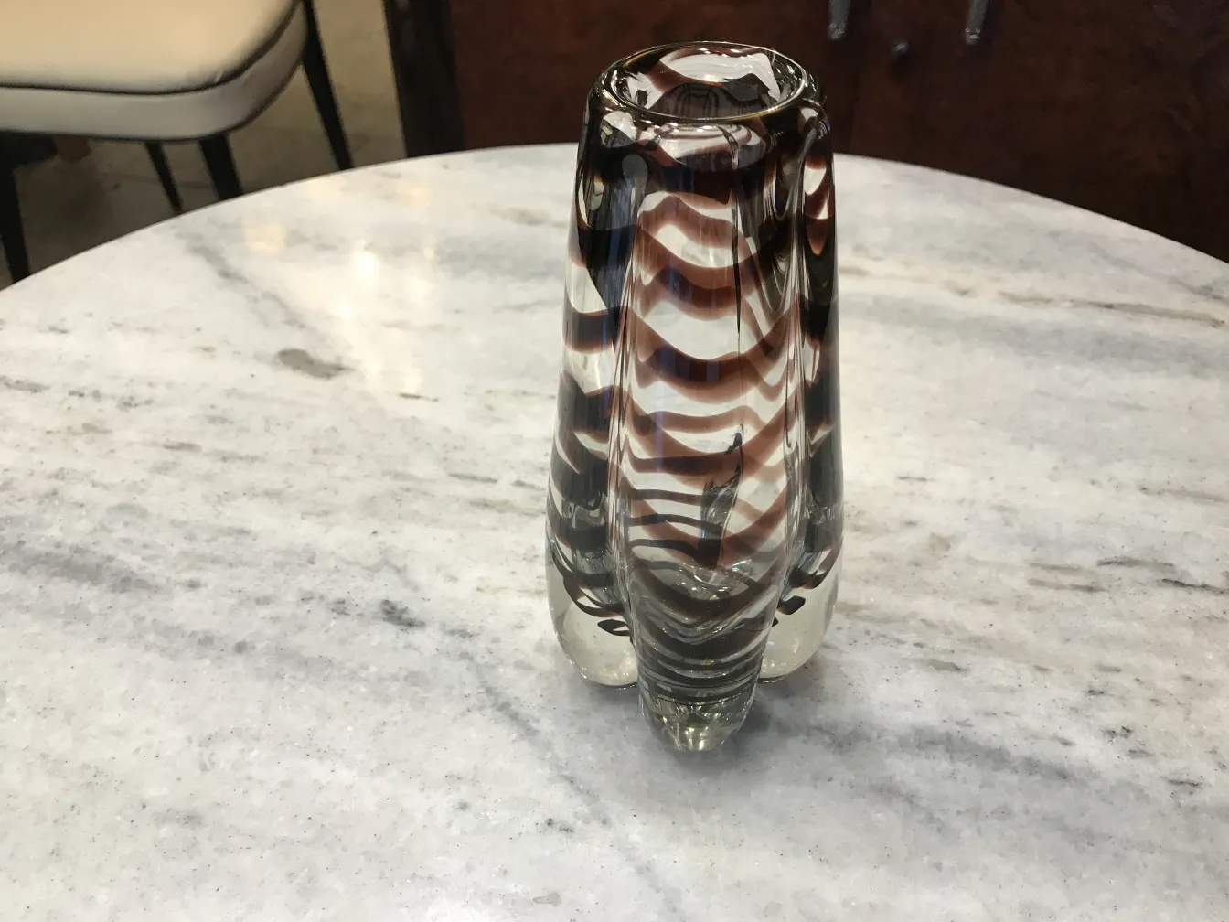 antike murano-vase mit gewelltem design in braunen und klaren tönen auf einem marmortisch