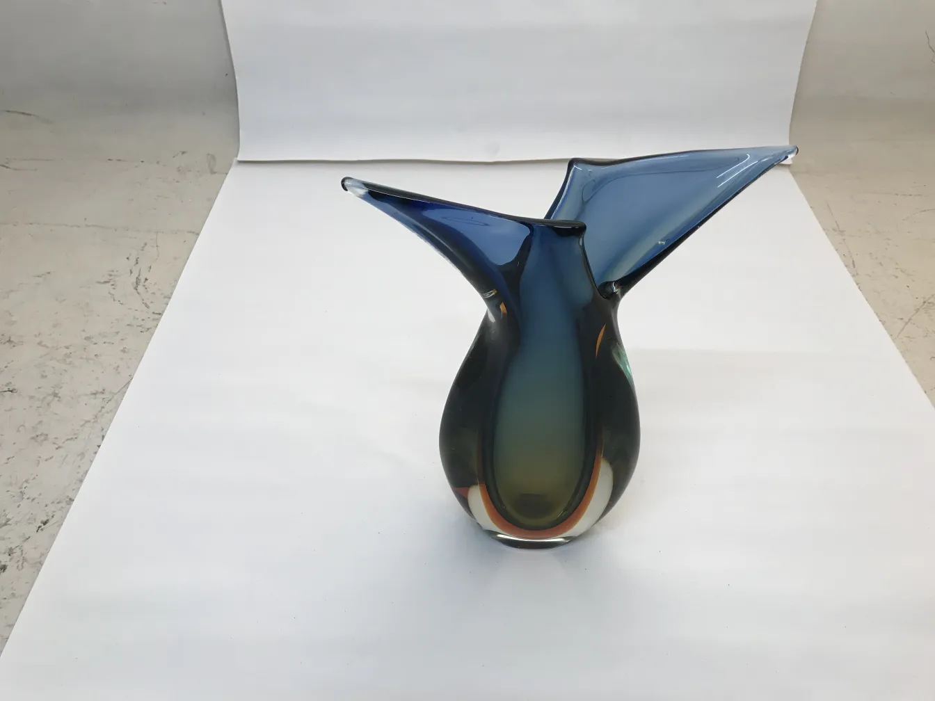 vaso de murano com forma elegante em azul e verde, em um fundo neutro