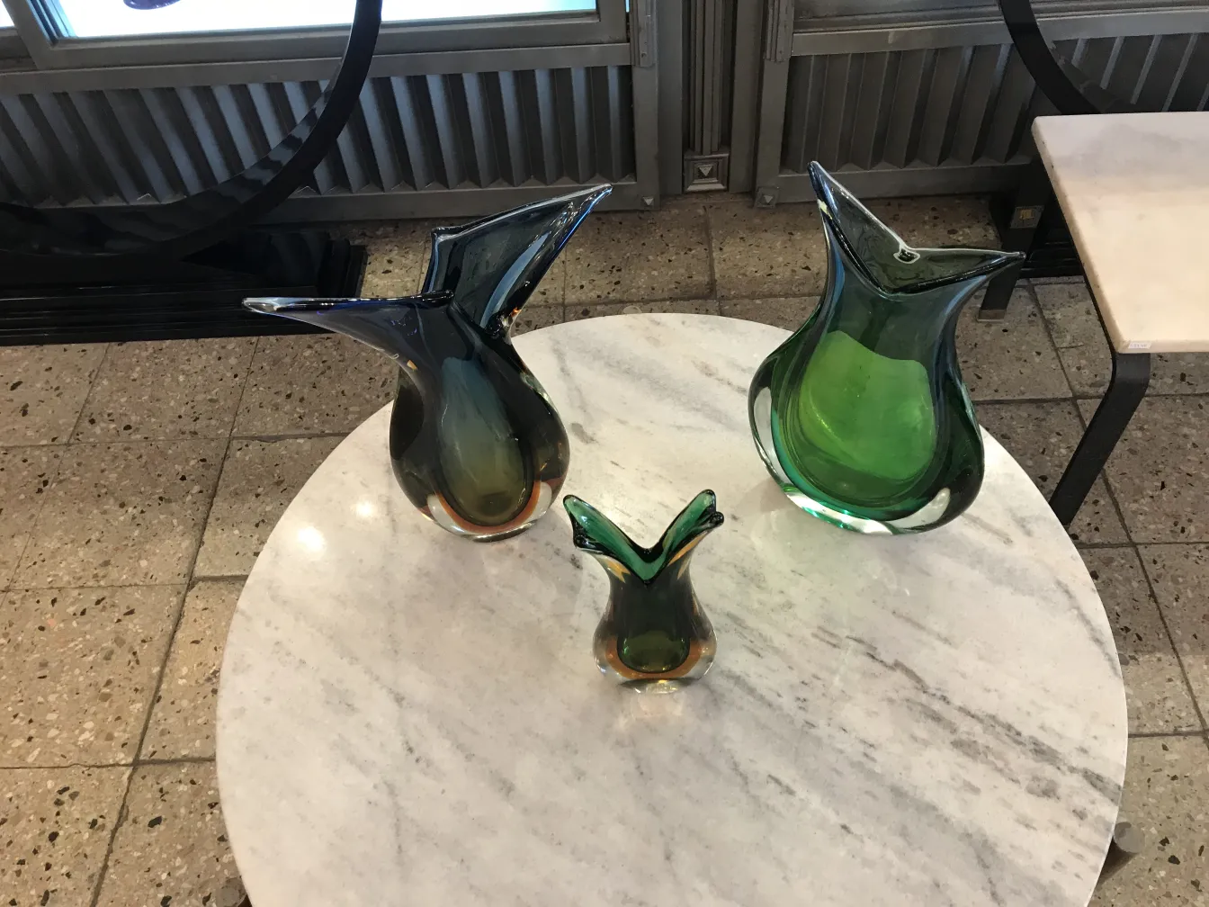 大理石テーブルの上にある3つのカラフルなムラーノの花瓶