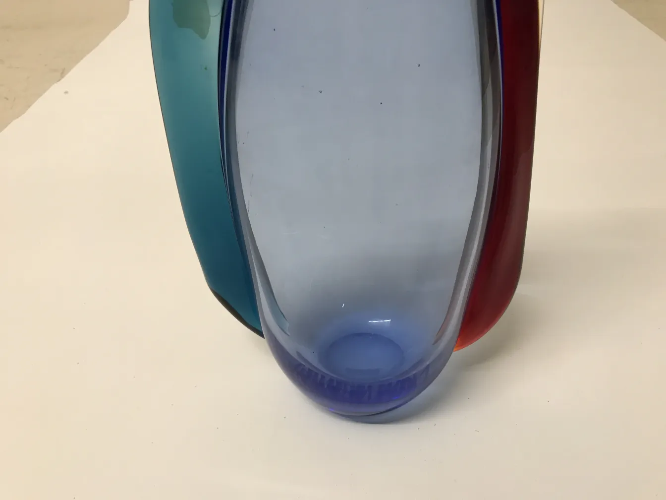 Un élégant vase Murano aux couleurs vives, mis en valeur sur un fond neutre.