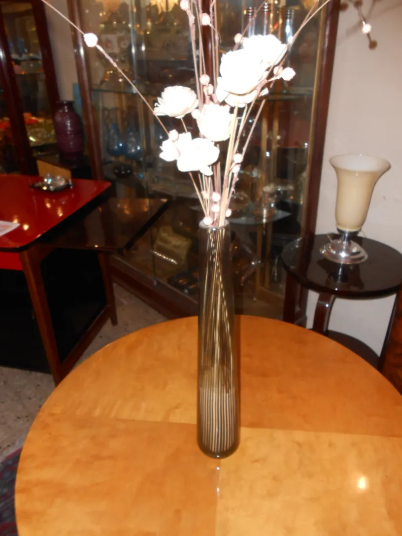 vaso de murano decorado com flores artificiais em um ambiente antigo, sobre uma mesa