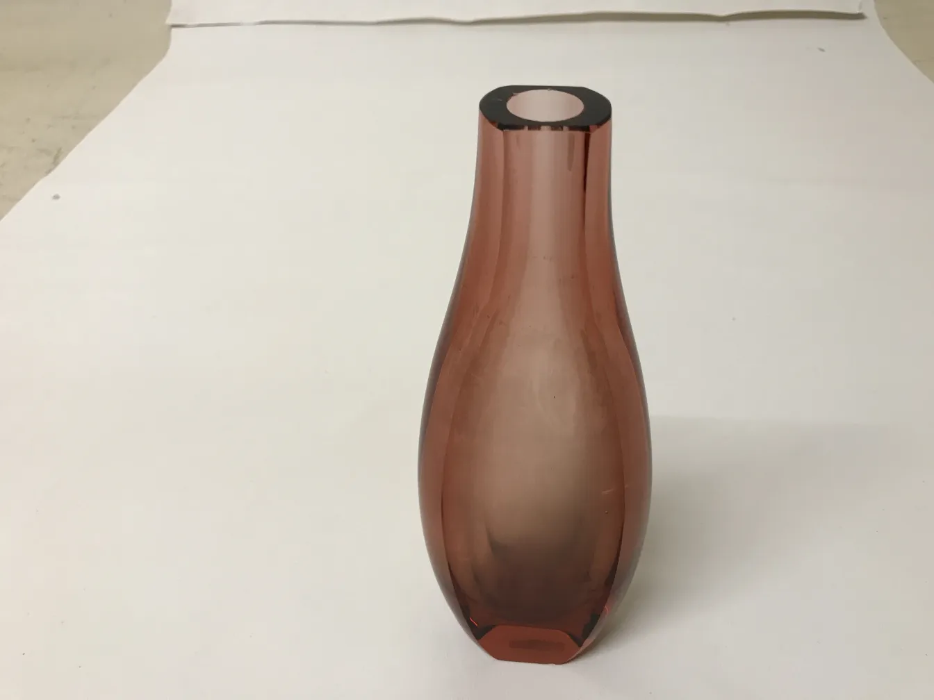 vaso di murano rosa con forma curva in un ambiente neutro