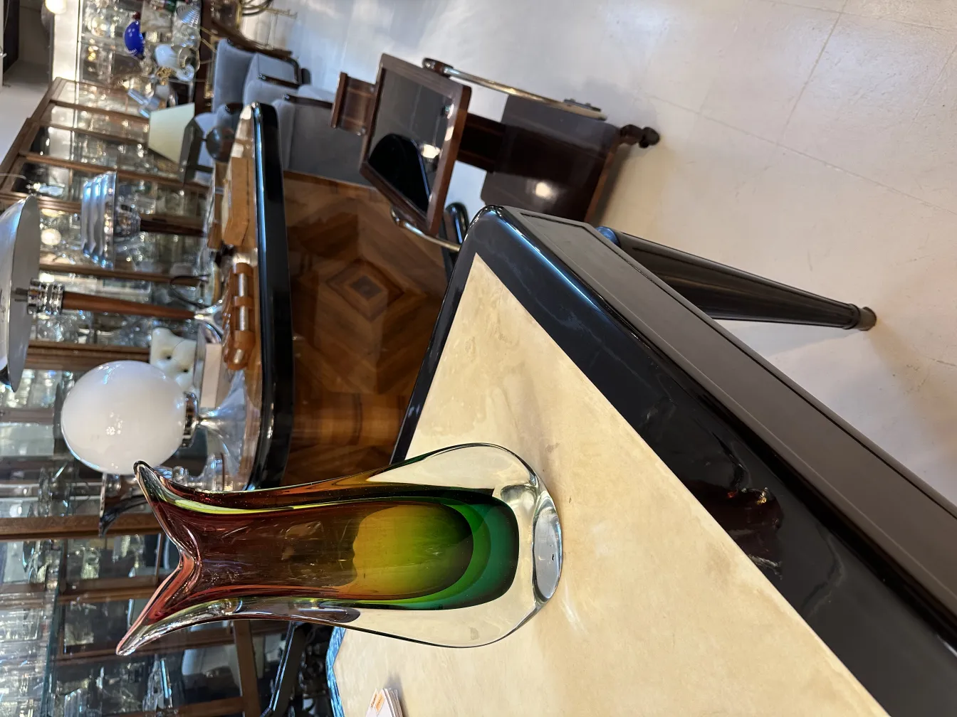 Vaso de Murano antigo em tons de verde e laranja sobre mesa elegante.