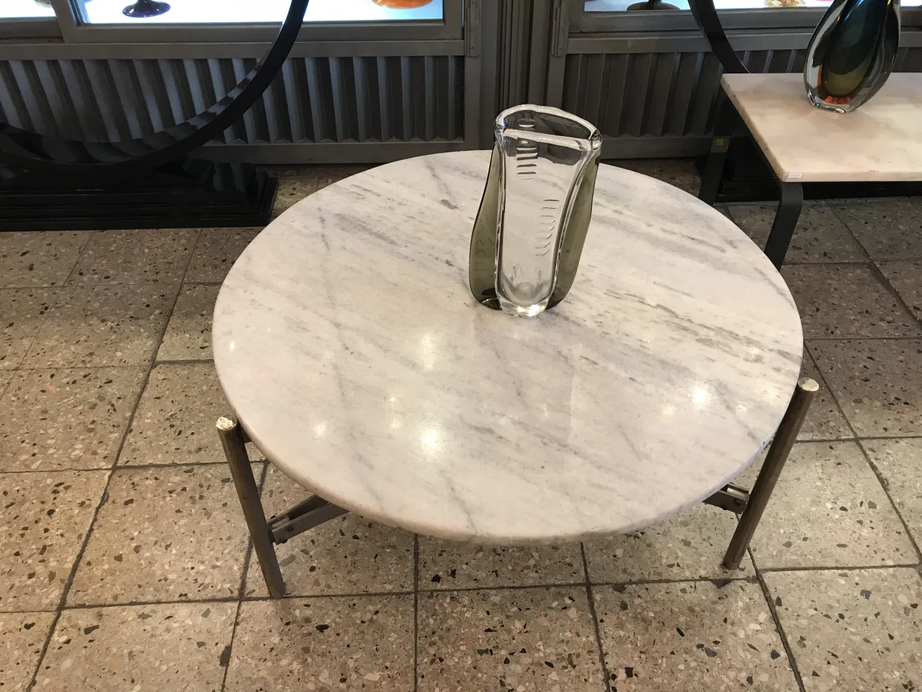 florero de murano en mesa blanca, rodeado de antigüedades