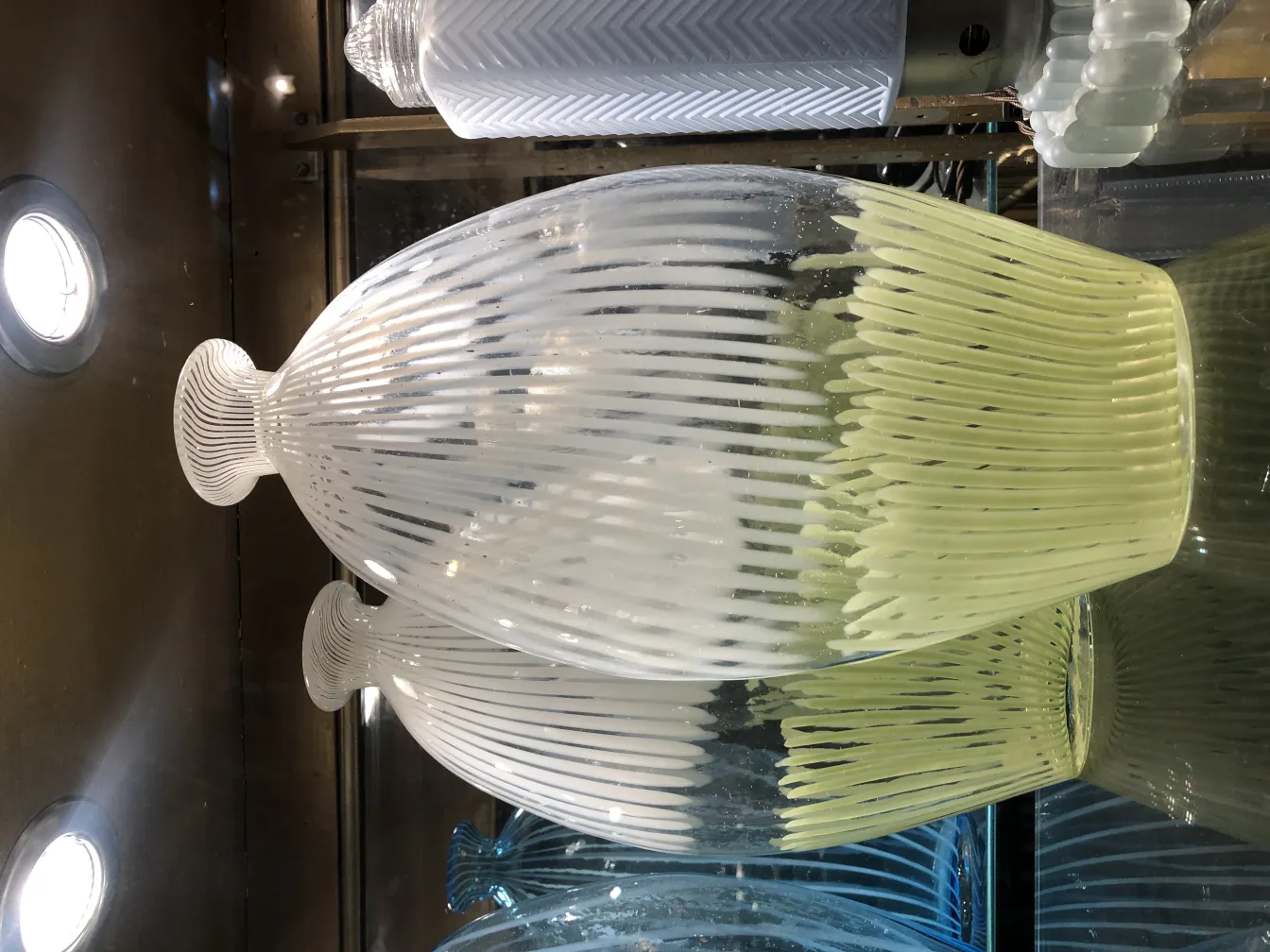 vase de murano avec design décoratif en tons de blanc et jaune, exposé avec d'autres objets anciens