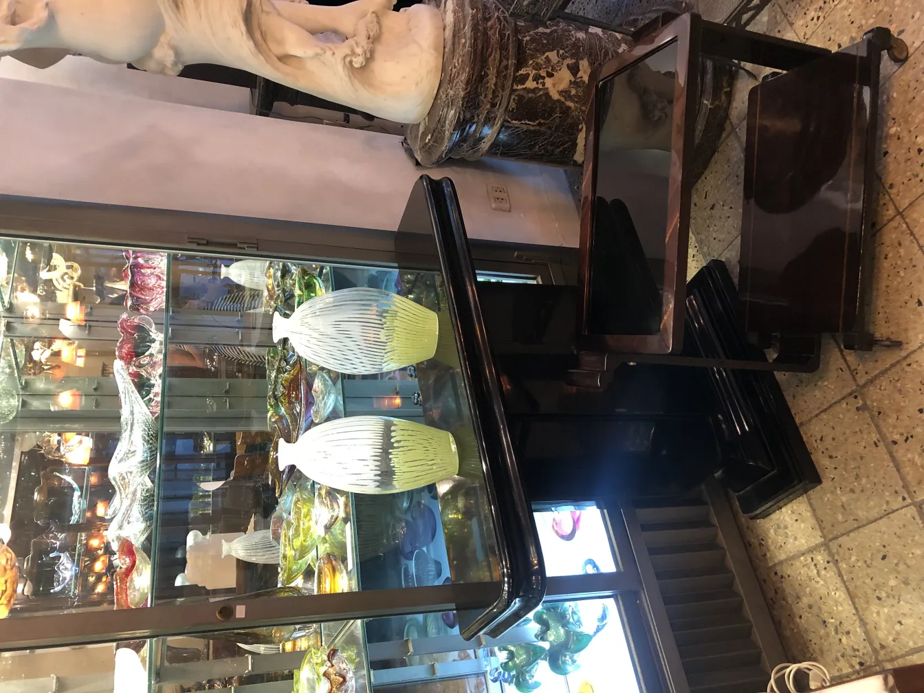 florero de murano antiguo con diseño de rayas claras y oscuras, en un entorno de exhibición elegante.