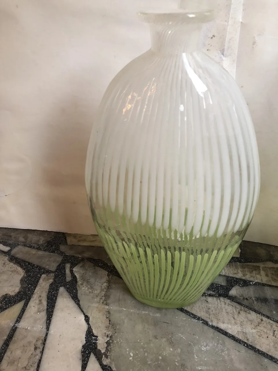 vaso de murano curvo com design elegante e verde na base, colocado sobre uma mesa