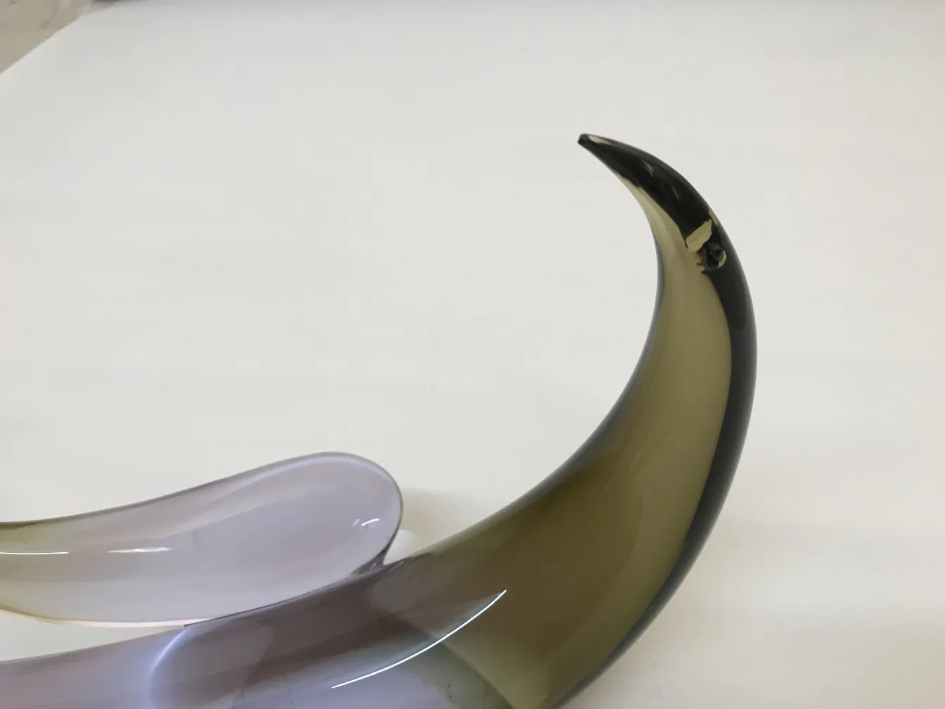 Scultura murano antica con forme fluide e colori variegati su sfondo chiaro.